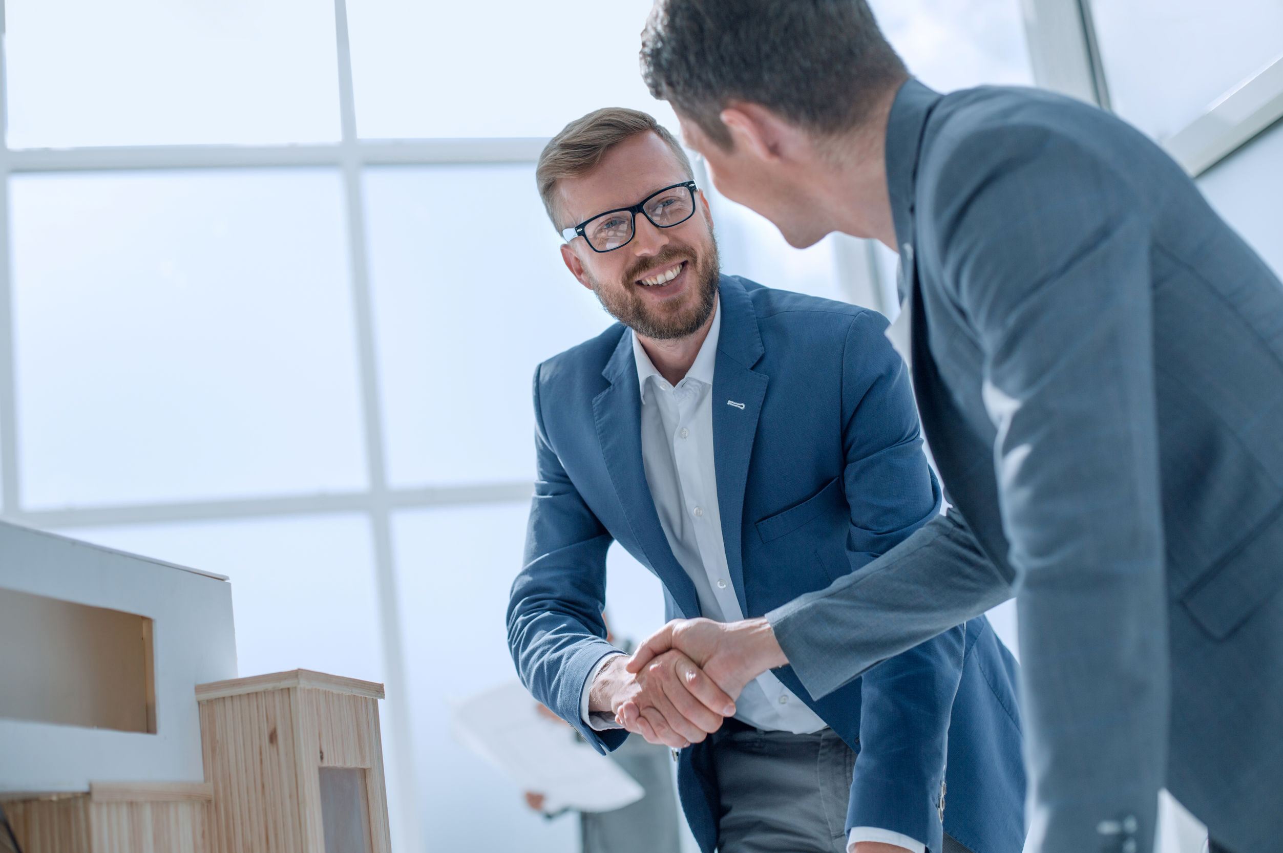 architect and designer shaking hands in creative office.